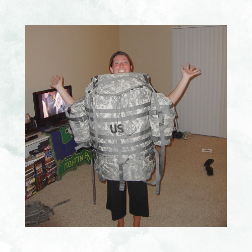 a young adult female is wearing a full army ruck sack in reverse