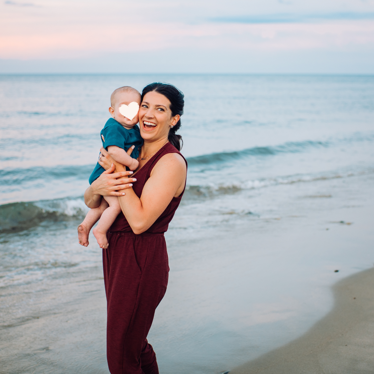 a mother and her infant son are pictured on an east coast beach smiling together