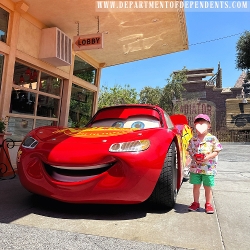toddler boy stands with lightning mcqueen in cars land at disneyland, california