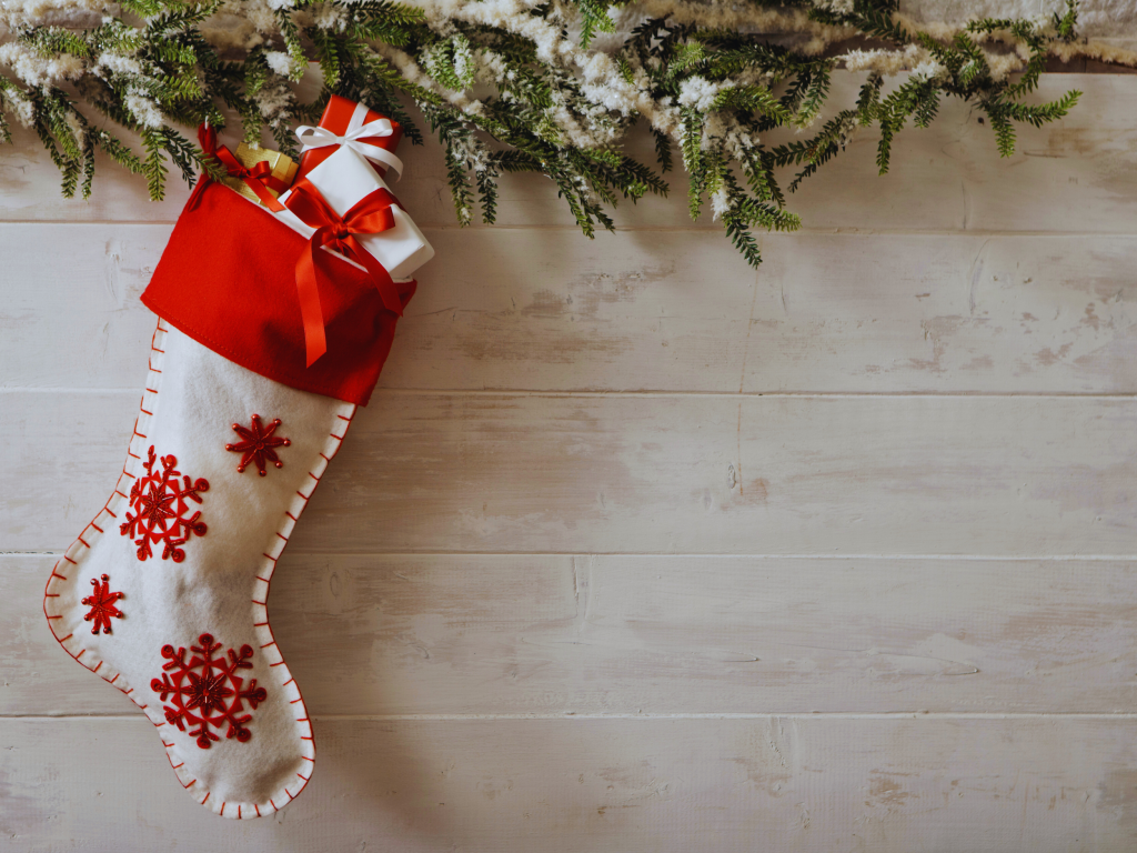 red and white christmas stocking hangs from a winter garland